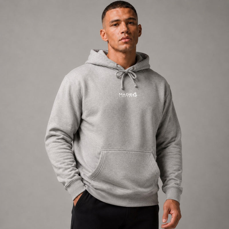 A man wearing a grey Made4Fighters hooded sweatshirt, photographed against a plain grey studio background.